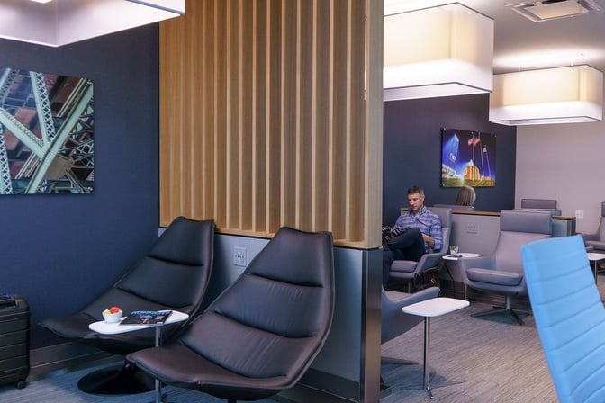 Seating area in The Club CLE at Cleveland Hopkins International Airport features lounge chairs and small tables for passenger relaxation.