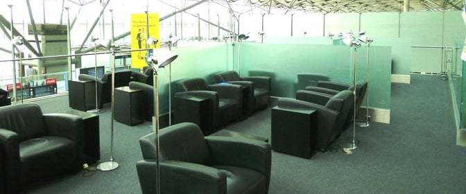 The seating area in the Lounge Koeln-Bonn at Cologne Bonn Airport features armchairs and individual lamps, offering a comfortable waiting space.