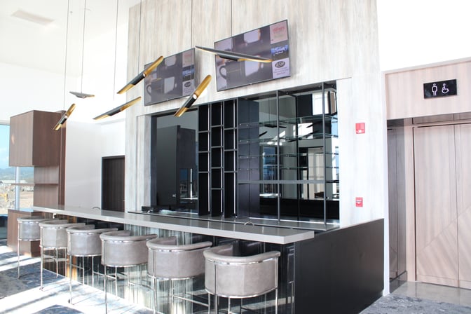 The bar area in the VIP Lounge at Comayagua International Airport features counter seating and mounted televisions for entertainment.