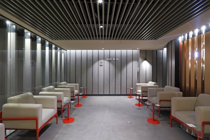 The seating area at Andes Lounge in Comodoro Arturo Merino Benítez International Airport features armchairs and small tables arranged in a spacious layout.