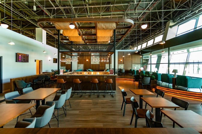 The Condor Lounge at Comodoro Arturo Merino Benítez International Airport features a central bar with counter seating and adjacent dining tables.