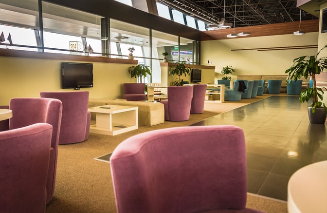The seating area in the Condor Lounge at Comodoro Arturo Merino Benítez International Airport features comfortable chairs and tables with airport views.