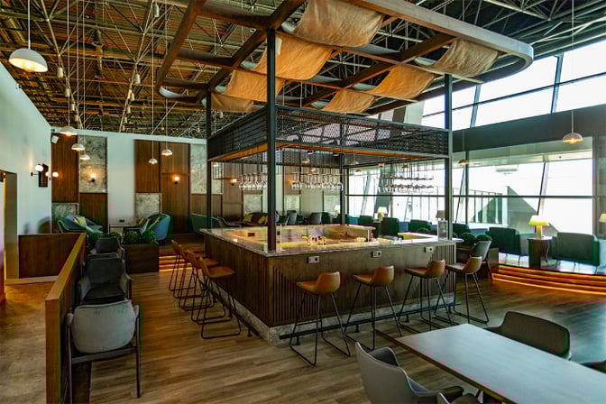 The Condor Lounge at Comodoro Arturo Merino Benítez International Airport features a central bar with surrounding seating and views of the tarmac.