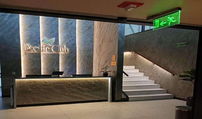 The entrance to the Pacific Club Lounge at Comodoro Arturo Merino Benítez International Airport features a reception desk and staircase.