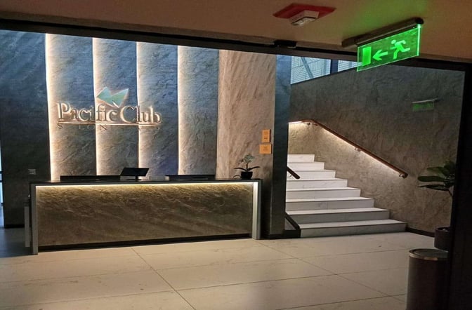 The entrance to the Pacific Club Lounge near Gate A08 features a reception desk and a staircase leading upwards.