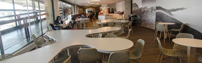 The seating area in the Salones VIP Pacific Club at Comodoro Arturo Merino Benítez International Airport offers tables with chairs and a self-serve food station.