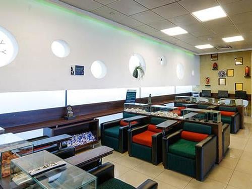 Seating area at Comodoro Arturo Merino Benítez International Airport "The Lounge" in the Domestic Terminal features armchairs and tables, offering a comfortable waiting space.