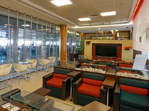 Seating area at Comodoro Arturo Merino Benítez International Airport "The Lounge" in the Domestic Terminal features armchairs and a television for passenger relaxation.
