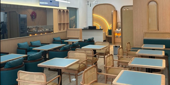 The SH Premium Lounge at Con Dao Airport features a seating area with tables and cushioned chairs, adjacent to a food service counter.