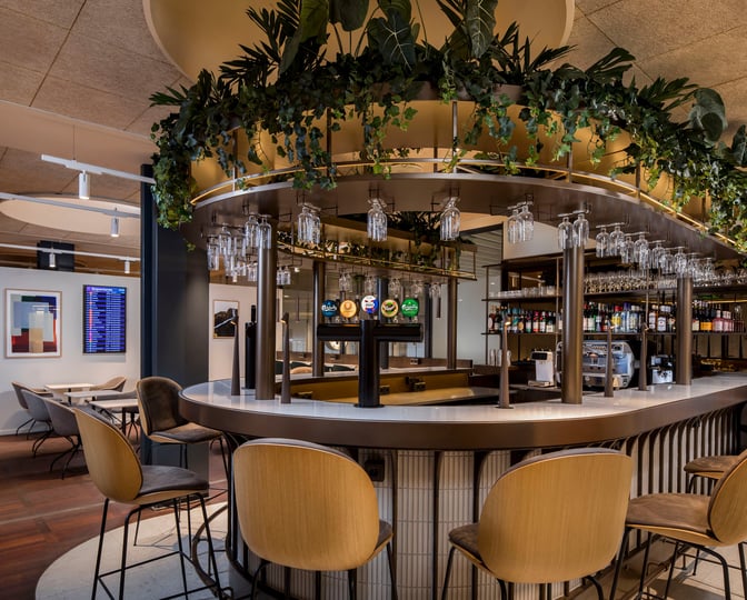 The Aspire Lounge at Copenhagen Airport features a bar with draft beer taps, hanging glasses, and seating for travelers.