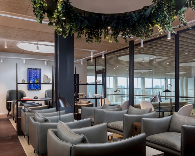 The Aspire Lounge at Copenhagen Airport features a seating area with comfortable chairs, tables, and a view of the airport tarmac.