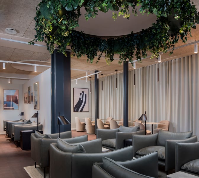 The Aspire Lounge at Copenhagen Airport features comfortable seating areas with tables and lamps, providing a relaxing space for travelers.