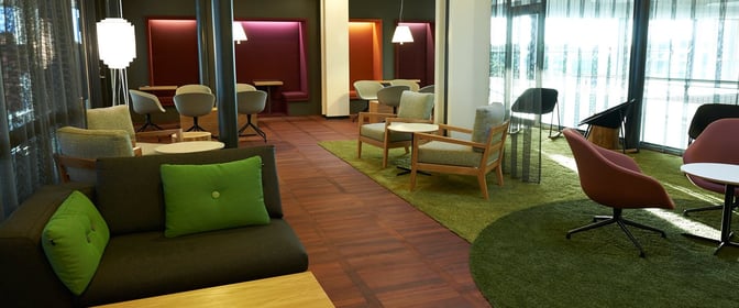 The Aspire Lounge at Copenhagen Airport features varied seating options, including armchairs and booths, with views of the airport exterior.