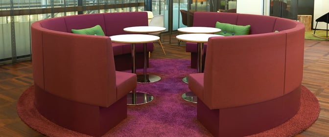 Circular booth seating in the Aspire Lounge at Copenhagen Airport provides semi-private spaces with multiple round tables for group gatherings.