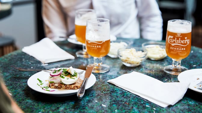A table at the Carlsberg Aviator Lounge features open-faced sandwiches and Carlsberg beer, offering a casual dining experience.
