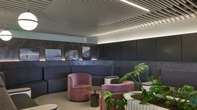 The seating area in the Goldair Handling Lounge at Ioannis Kapodistrias Airport features curved couches, individual chairs, and decorative plants.