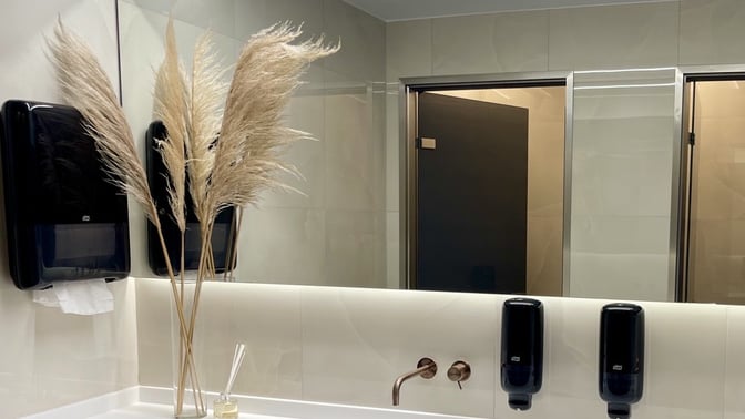 The restroom area in the Goldair Handling Lounge features multiple stalls, wall-mounted soap dispensers, and decorative elements near the sinks.