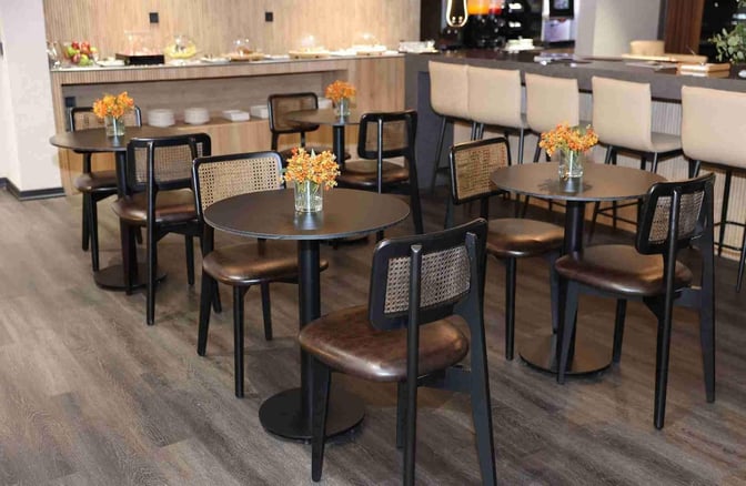 The Celebi COV Domestic Lounge at Cukurova International Airport features a seating area with round tables and chairs near a food service counter.