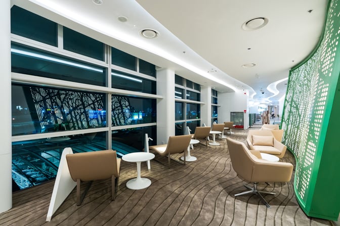 The seating area in Vanda Lounge at Da Nang International Airport features comfortable chairs and tables with large windows offering airport views.
