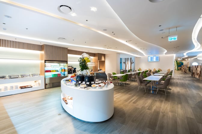 The Vanda Lounge at Da Nang International Airport features a self-serve food station with seating areas and a beverage cooler.
