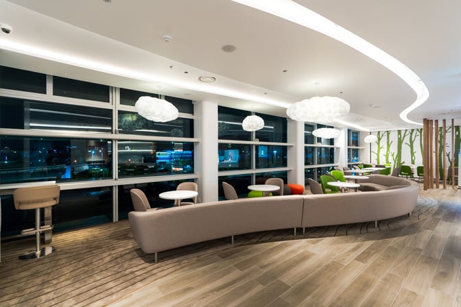 The seating area at Vanda Lounge, Da Nang International Airport, features curved sofas and tables with views of the airport.