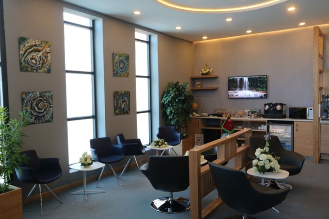 The Pearl Lounge at Dakhla Airport features seating with small tables, a television, and a refreshment area with a coffee machine.