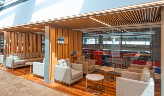 The seating area in the CIP Lounge at Dalaman Airport features comfortable chairs and sofas with small tables, offering a view of the terminal.