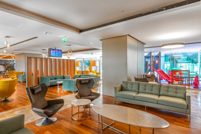 The CIP Lounge at Dalaman Airport features a seating area with various chairs and sofas, adjacent to a visible children's play area.