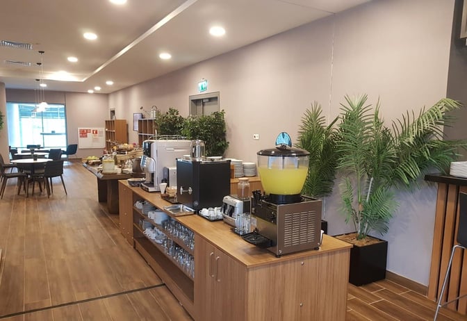 The DLM Lounge at Dalaman Airport features a self-serve beverage station with coffee machines and juice dispensers, alongside seating areas.