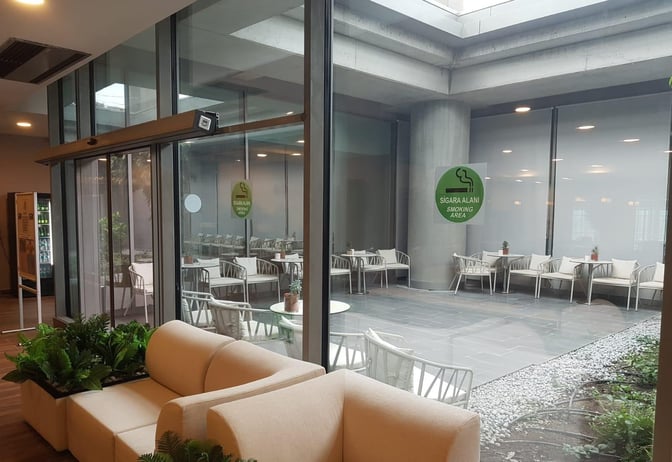 The DLM Lounge at Dalaman Airport features a designated smoking area with outdoor seating visible through large glass windows.