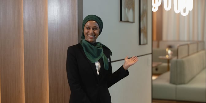 The Plaza Premium First lounge at Dallas-Fort Worth International Airport features a welcoming staff member near the seating area.