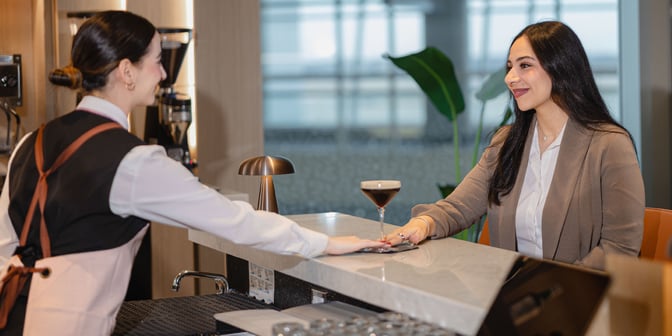 A staff member serves a guest at the bar in the Plaza Premium Lounge at Dallas-Fort Worth International Airport.