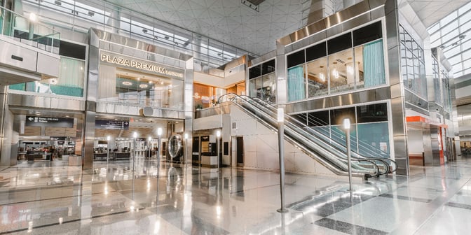 The Plaza Premium Lounge entrance at Dallas-Fort Worth International Airport is located on an upper level, accessible via escalators.