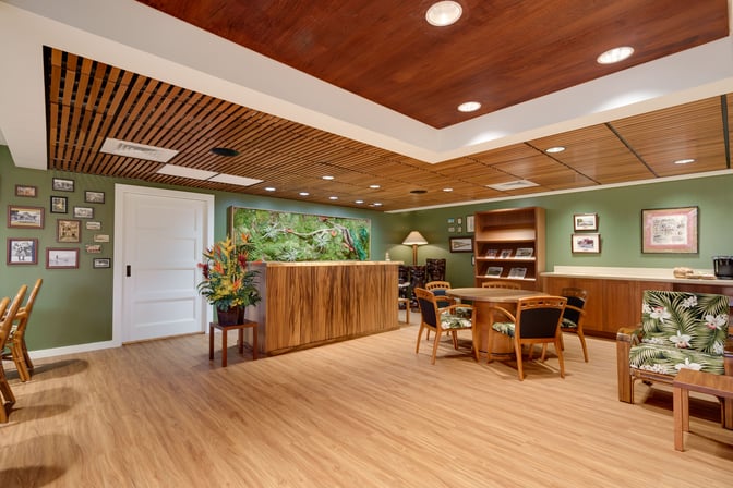 The IASS Hawaii Lounge at Daniel K. Inouye Honolulu International Airport features seating areas with tables, chairs, and a decorative reception desk.