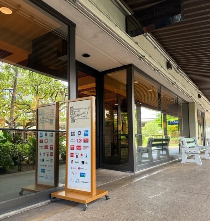 The entrance to the IASS Hawaii Lounge at Daniel K. Inouye Honolulu International Airport features a sign displaying partner logos.
