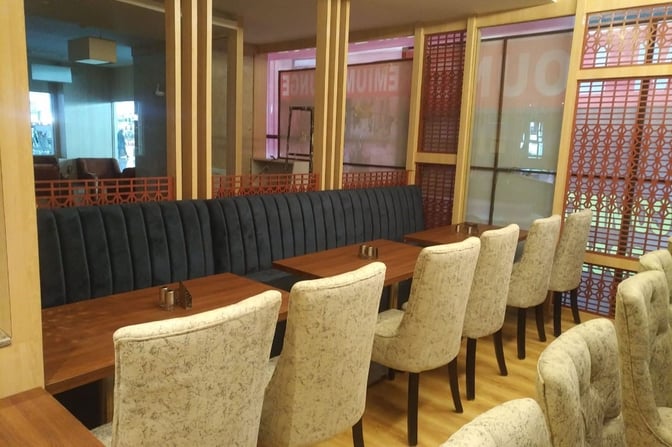 Booth seating at the Primus Lounge in Devi Ahilyabai Holkar Airport offers semi-private dining with individual tables and cushioned chairs.