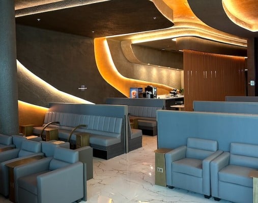 The seating area in the Salones VIP Pacific Club features comfortable chairs and booths, with a coffee station in the background.