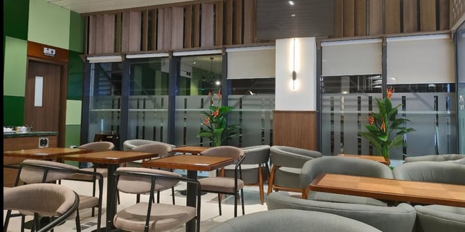 The seating area in SH Premium Lounge at Dien Bien Phu Airport features tables and chairs with privacy partitions and decorative plants.