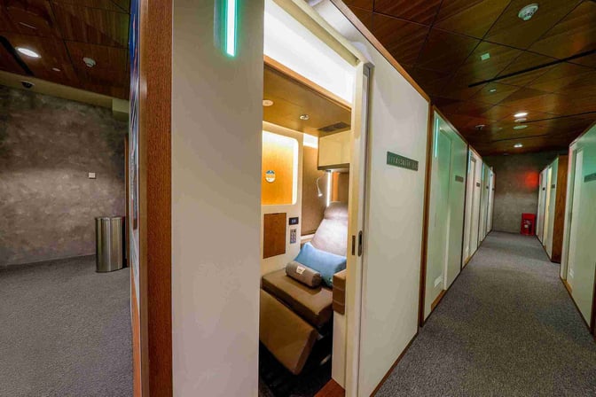 Private sleeping pods at Doha Hamad International Airport's Sleepover South Node offer reclining seats and personal lighting for passenger comfort.