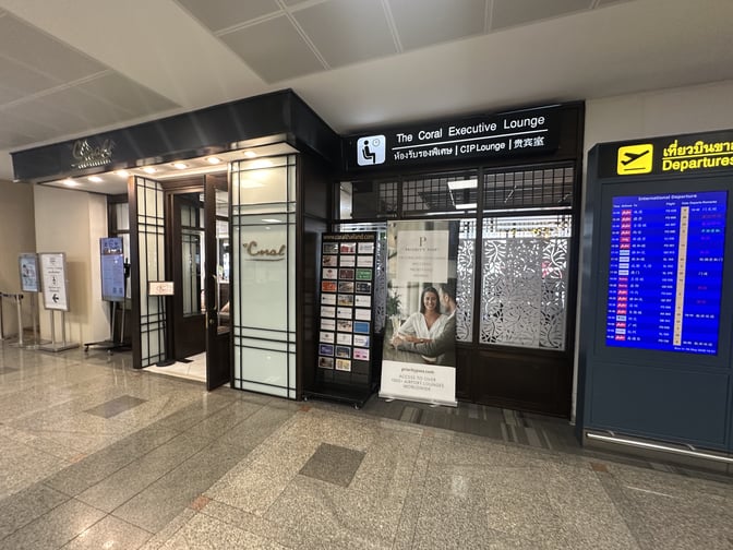 The Coral Executive Lounge entrance at Don Mueang International Airport is located near the departures area, featuring signage and promotional displays.
