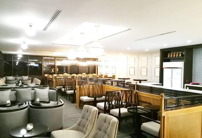 The Coral Finest Business Class Lounge at Don Mueang International Airport features a seating area with cushioned chairs and tables for relaxation.