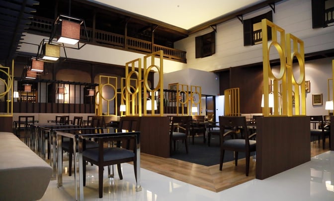 The seating area in Miracle Lounge No. 2 at Don Mueang International Airport features tables and chairs with decorative partitions.