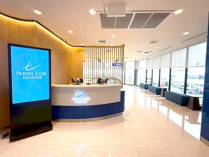 The Travel Club Lounge entrance at Don Mueang International Airport features a reception desk and seating with airport views.