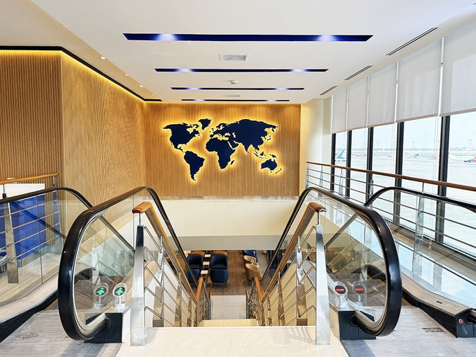 The Travel Club lounge at Don Mueang International Airport features an escalator entrance with a world map display and airport views.
