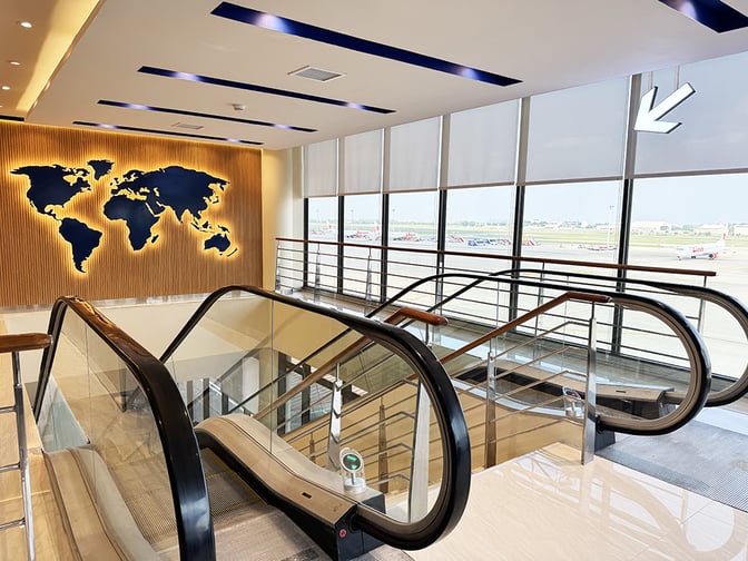 The Travel Club lounge entrance at Don Mueang International Airport features escalators and a world map wall display near the windows.
