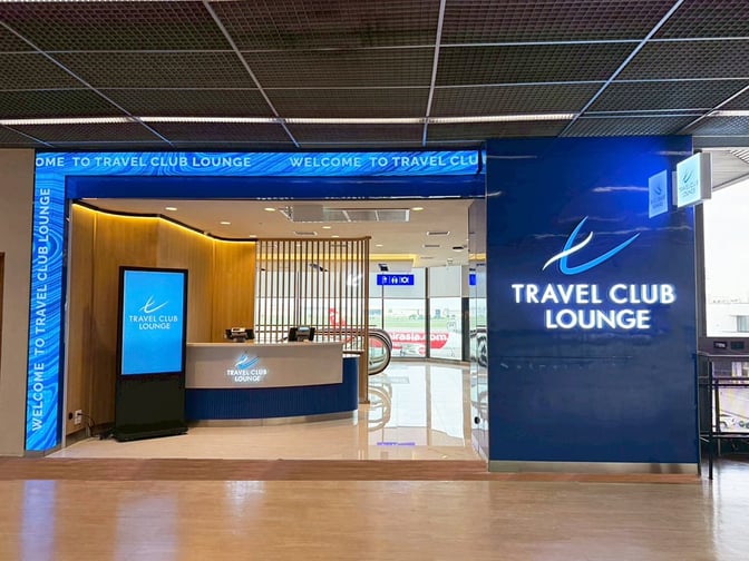 The entrance to the Travel Club Lounge at Don Mueang International Airport features a reception desk and digital signage.