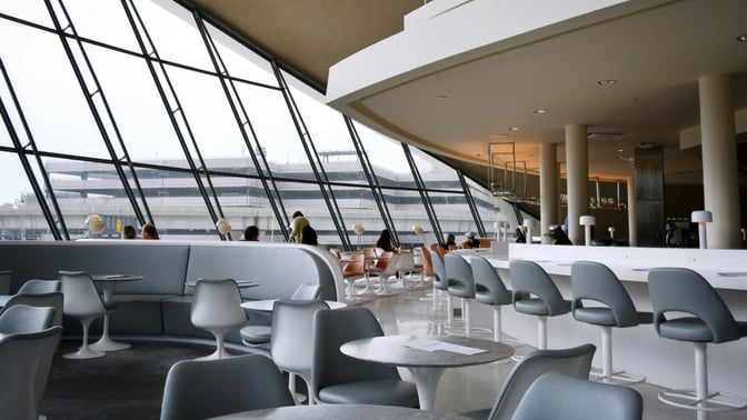 The seating area in the Miracle Lounge at Don Mueang International Airport features tables and chairs with large windows offering airport views.