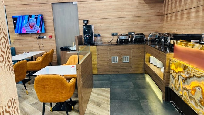 The Airr Lounge at Dr. Babasaheb Ambedkar International Airport features a dining area with tables, chairs, and a buffet station.