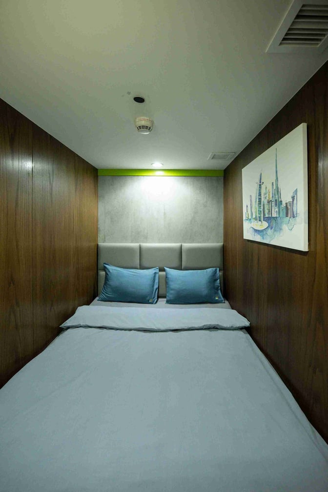 A sleep pod in Dubai International Airport's Concourse D offers a compact bed space with pillows and wall art for travelers.