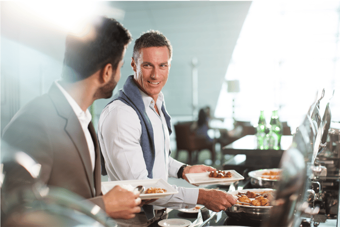 Guests at the marhaba Lounge in Dubai International Airport Terminal 2 serve themselves from a buffet with various hot food options.